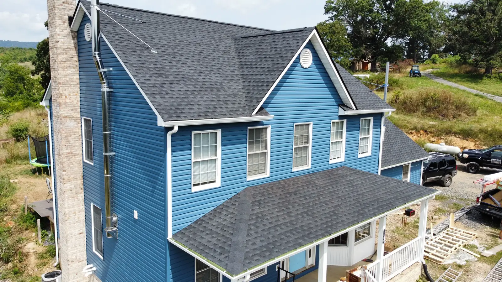 A blue two-story house with a gray roof seen from the air