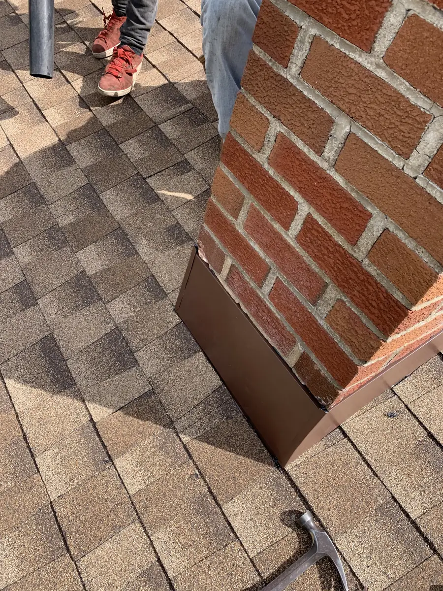 Metal flashing where a brick chimney meets a shingle roof