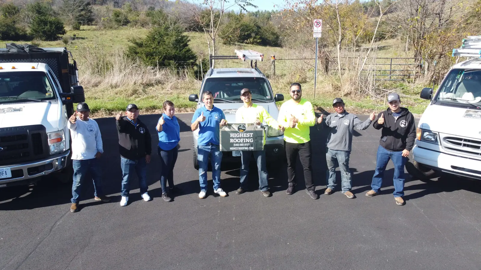 The Highest Roofing crew giving a thumbs up beside their white trucks