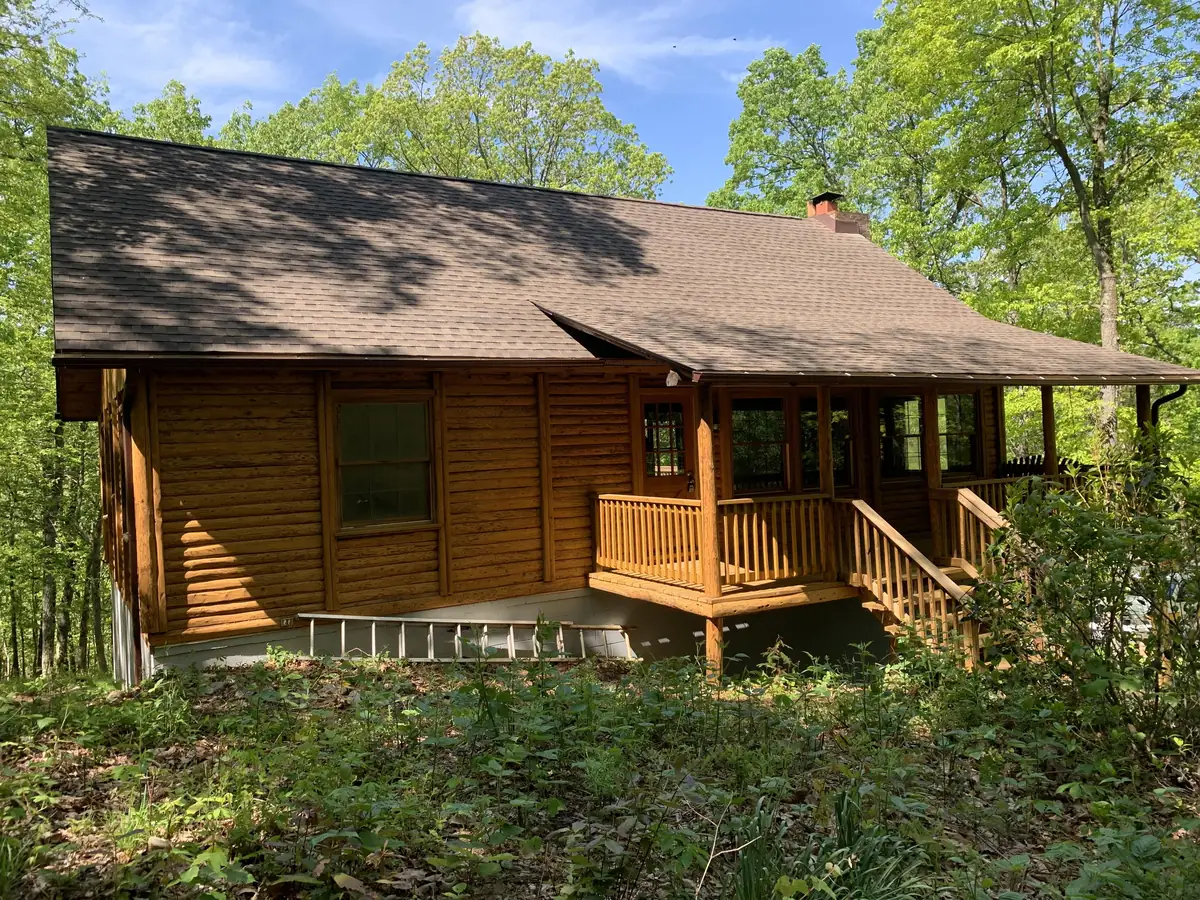 A log cabin with a brown shingle roof in the woods