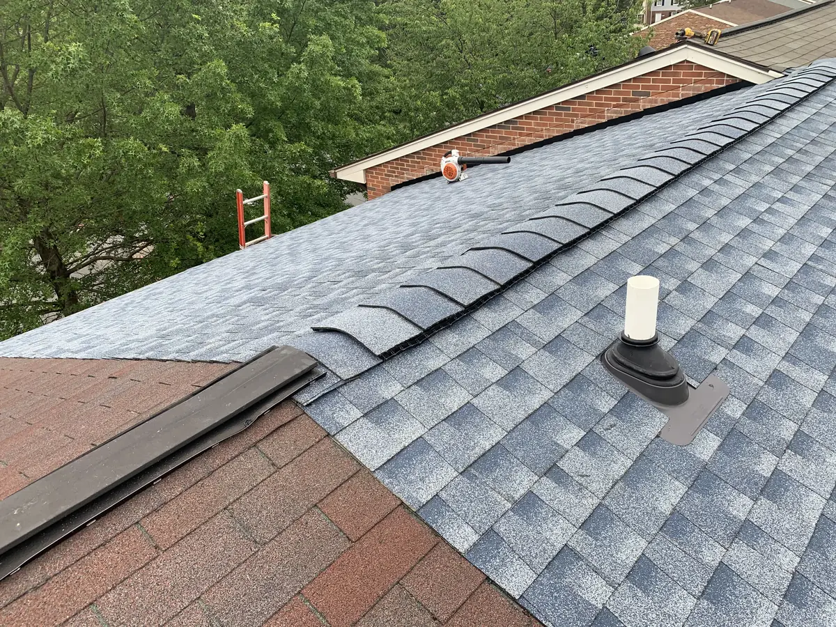 New blue-gray shingles meeting older red shingles at a ridge