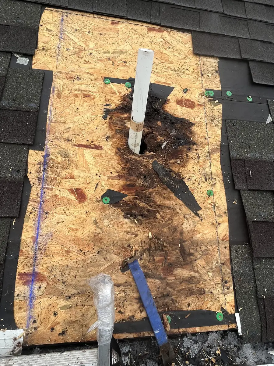 Rotted roof decking exposed around a vent pipe