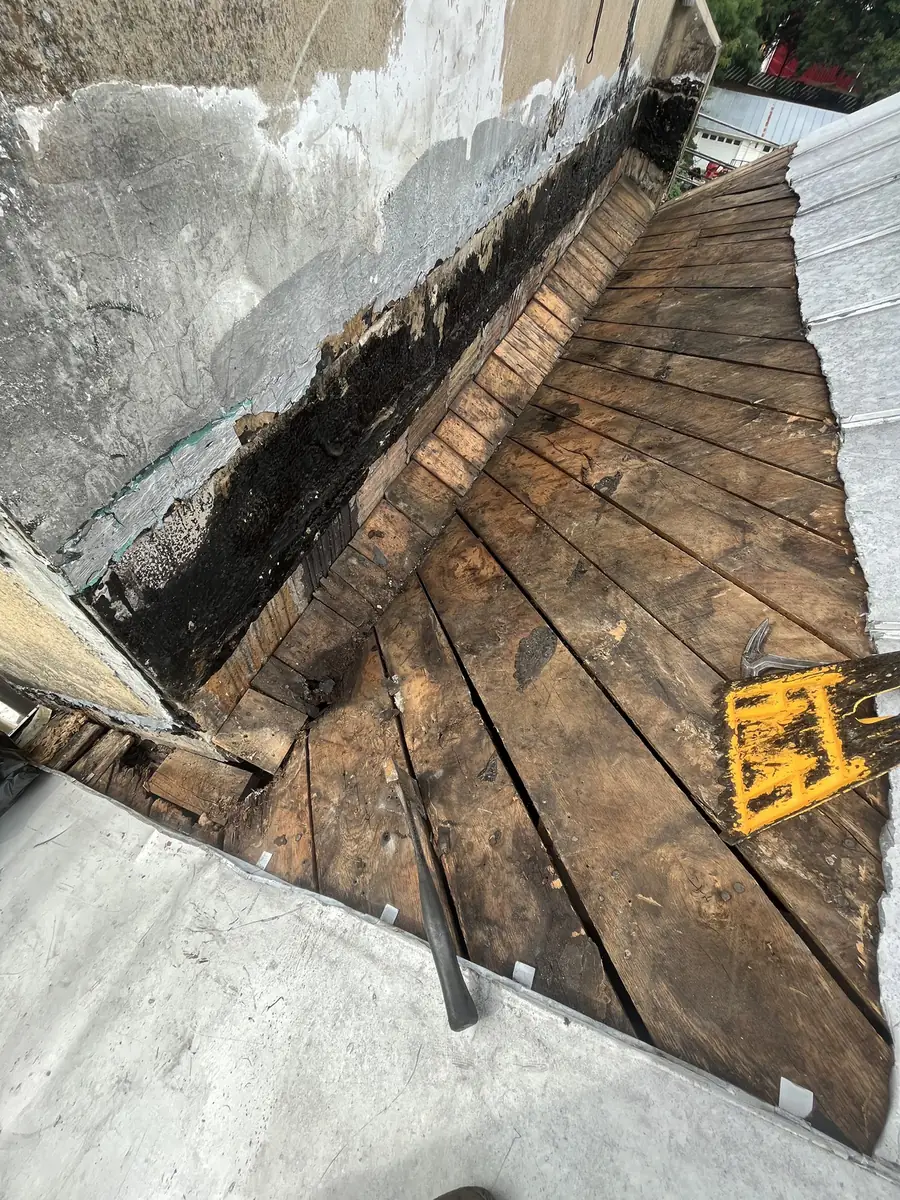 Rotted wooden decking exposed in a roof valley