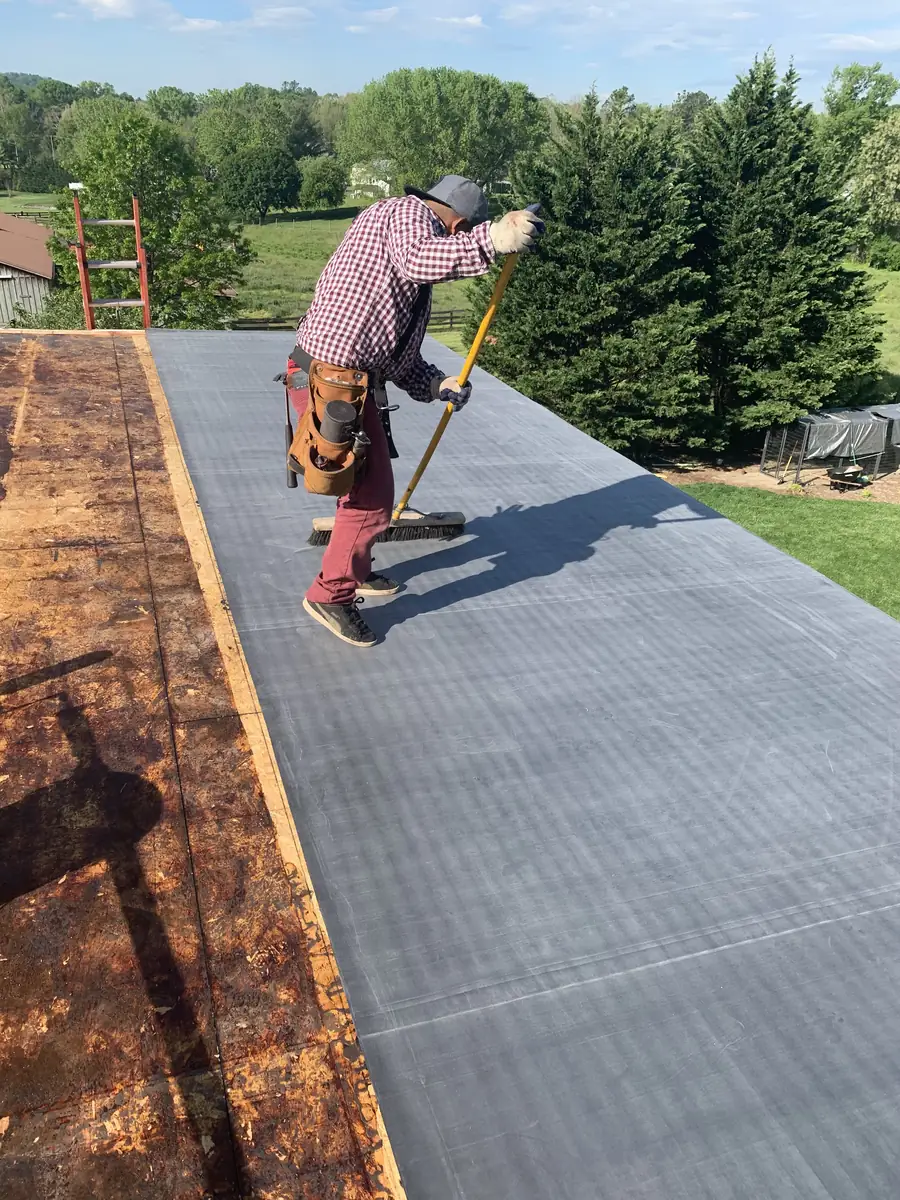 A roofer tearing off old shingles down to the decking