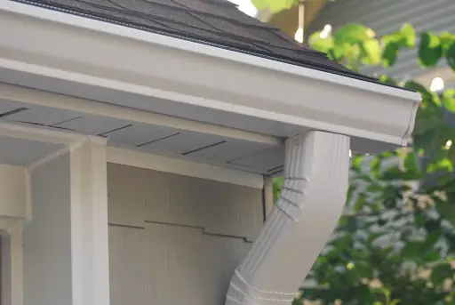 A white gutter along a gray shingle roof edge
